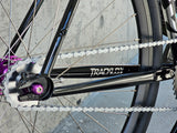 Close-up of TrackloX Midnight Mirage TLX20MM rear drivetrain, featuring a white KMC Rust Buster chain, flip-flop hub with purple anodized accents, and a black track frame. Designed for urban riding, bikepacking, and tracklocross