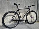 TrackloX Midnight Mirage TLX20MM – a sleek black single-speed fixie bike with purple accents, rugged 35c Arisun tires, and a lightweight chromoly frame. Ideal for urban commuting, bikepacking, and tracklocross