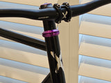 Close-up of the XFIXXI TrackloX Urban Bike's headset and handlebar. Featuring a black aluminum riser handlebar with the 'XFIXXI' logo, a purple anodized headset, and a lightweight chromoly frame